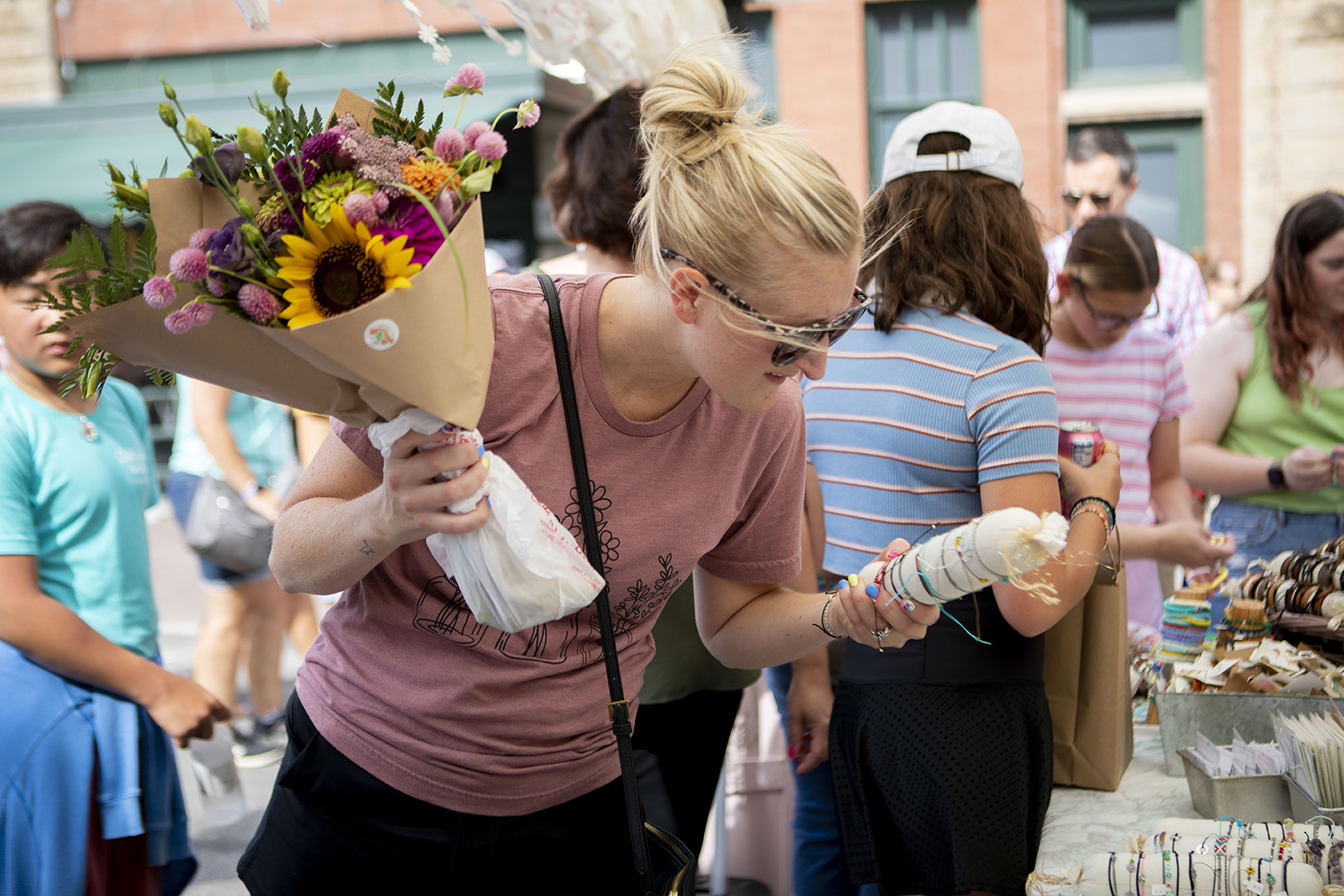 A woman holds two bouquets of flowers as she shops at a farmers market in Lincoln's Haymarket.