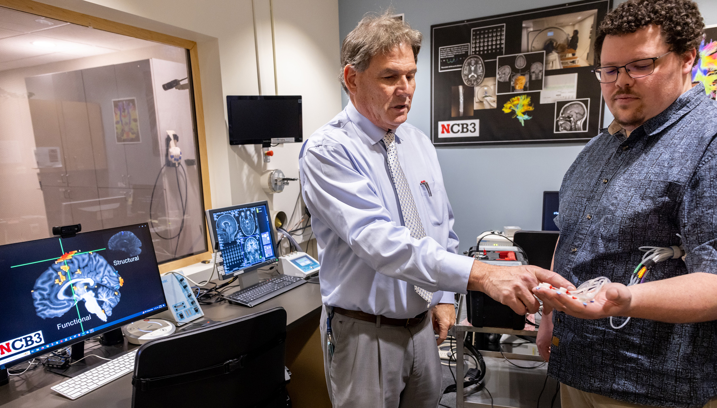 Steven Barlow, Corwin Moore Professor in special education and communication disorders, explains the pTACS' thermoplastic tactile ‘touch’ capsules on the hand of Jacob Greenwood, doctoral candidate in biological systems engineering.
