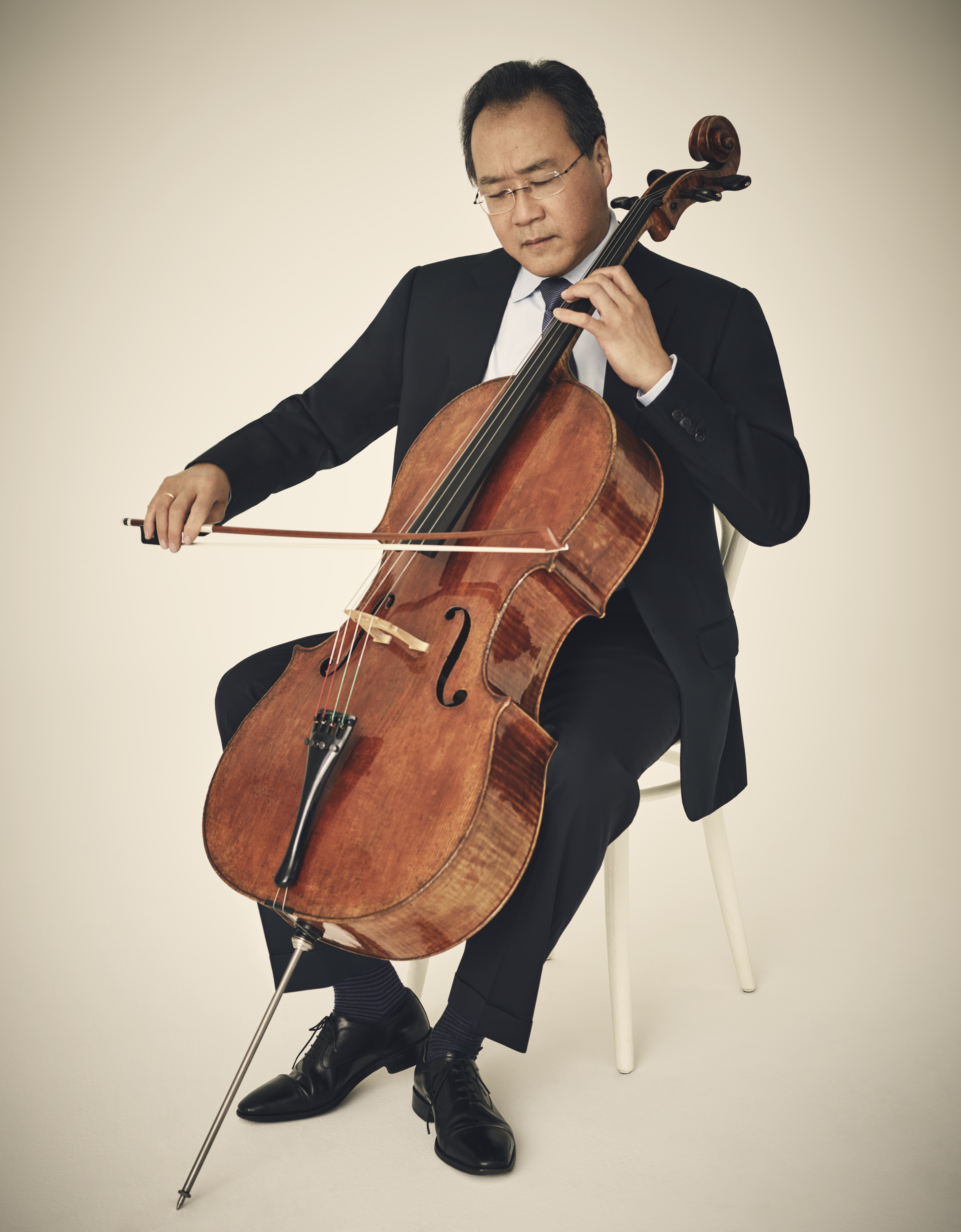 Yo-Yo Ma plays the cello, wearing a black-and-white suit.