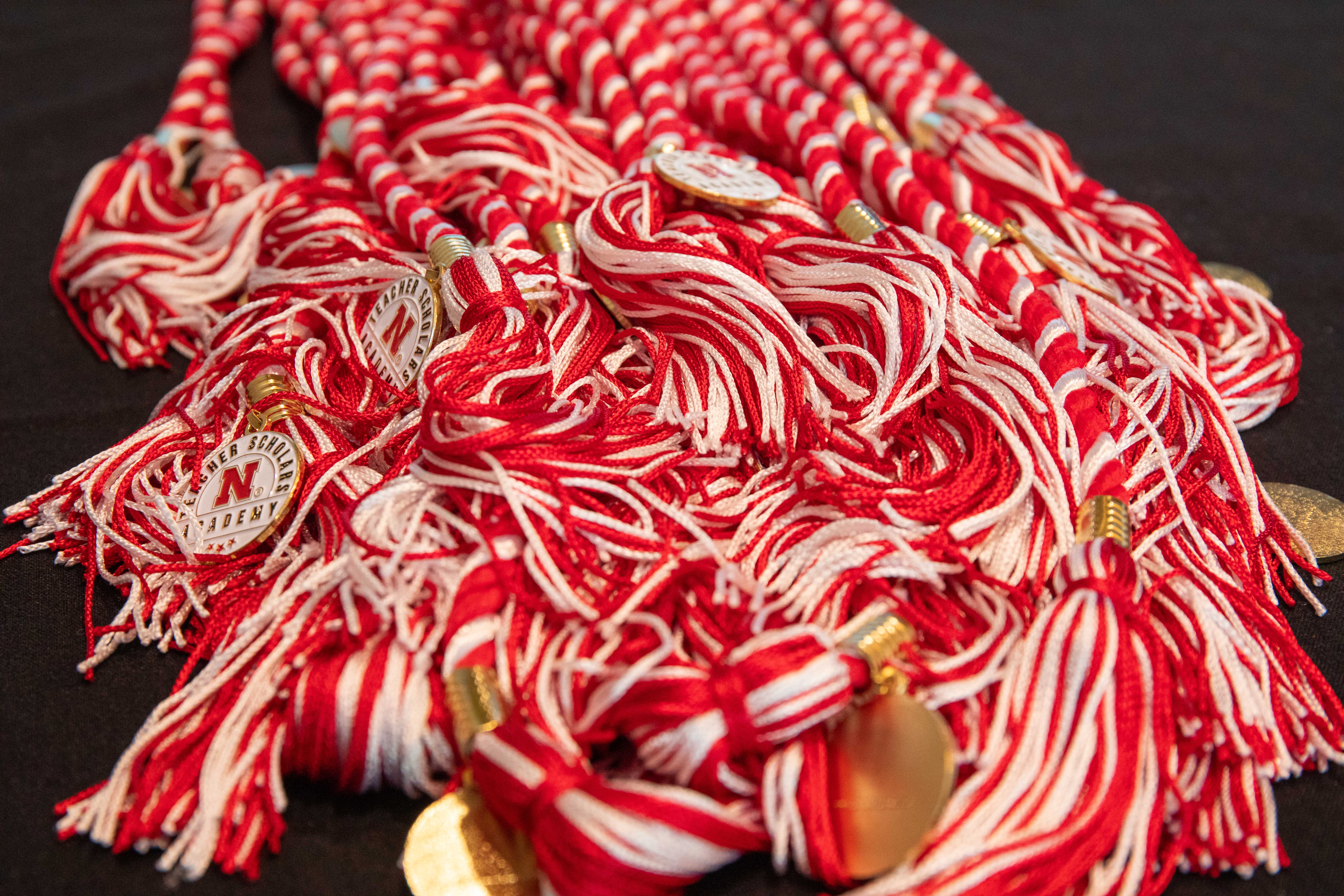 A pile of red-and-white honor cords with medallions that say "Teacher Scholars Academy."