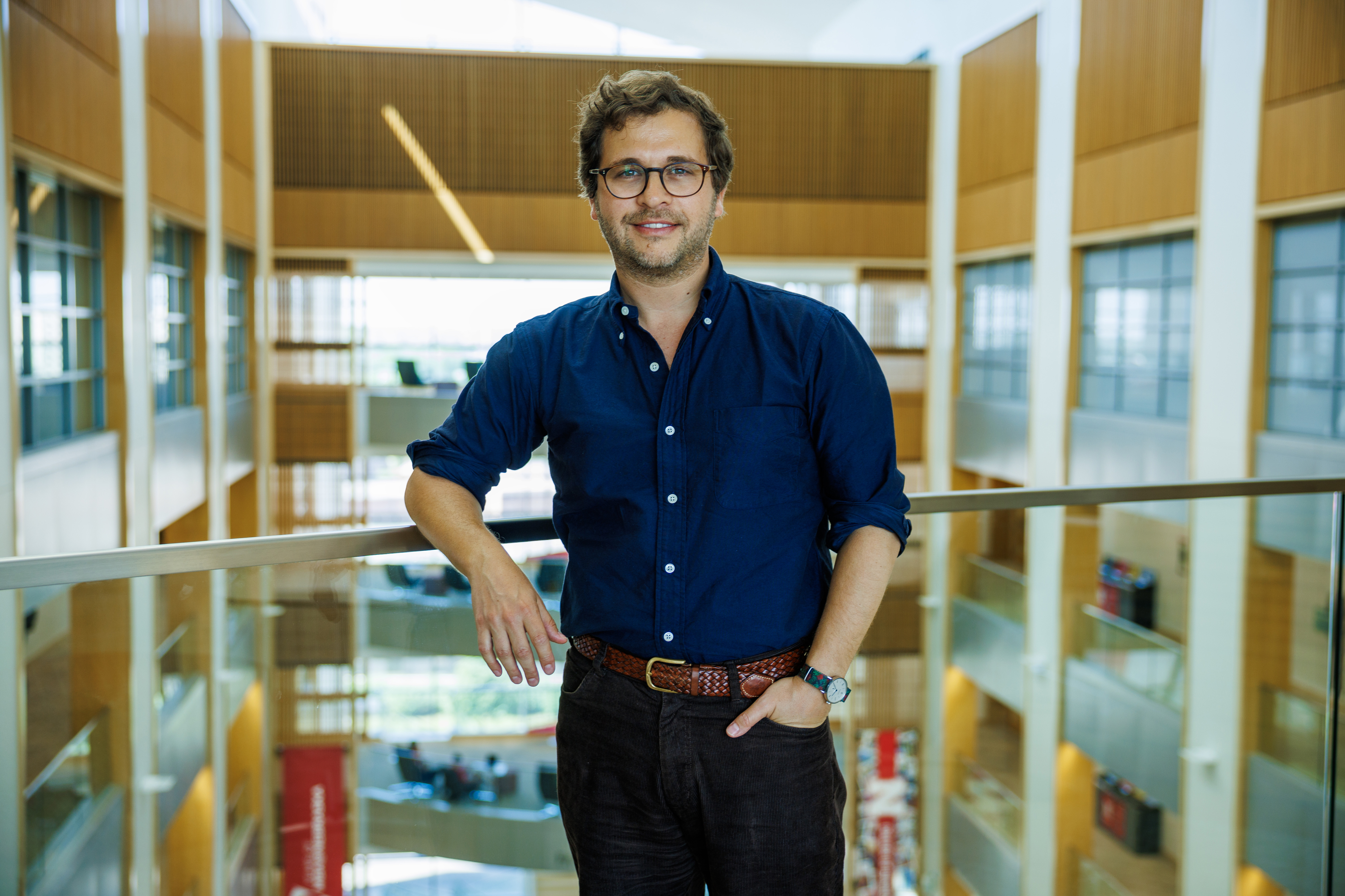 Daniel Tannenbaum, Georgia and Jim Thompson Associate Professor of Economics, stands next to a rail around the atrium to Howard L. Hawks Hall.