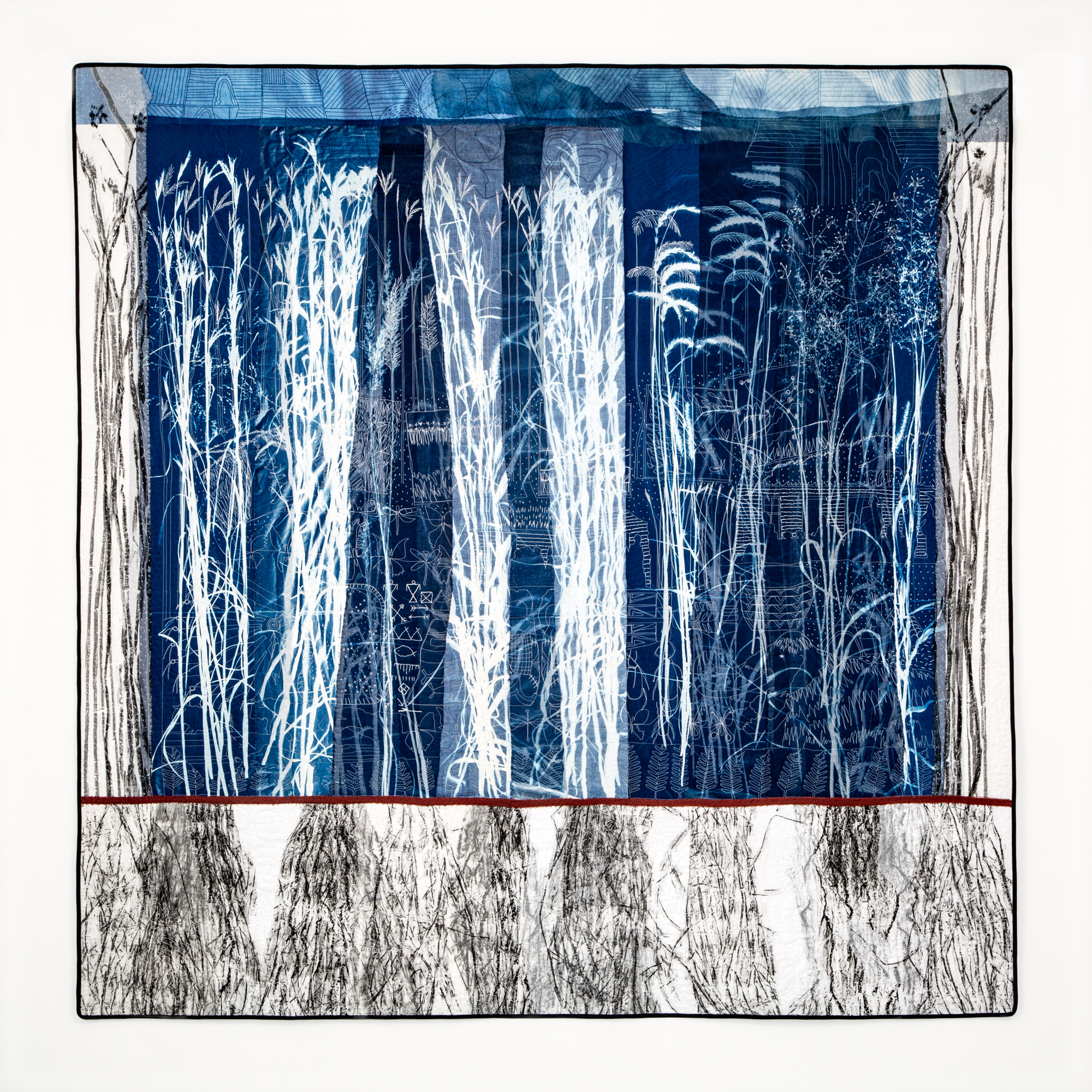 A quilt featuring cyanotype images of prairie grass and their roots.