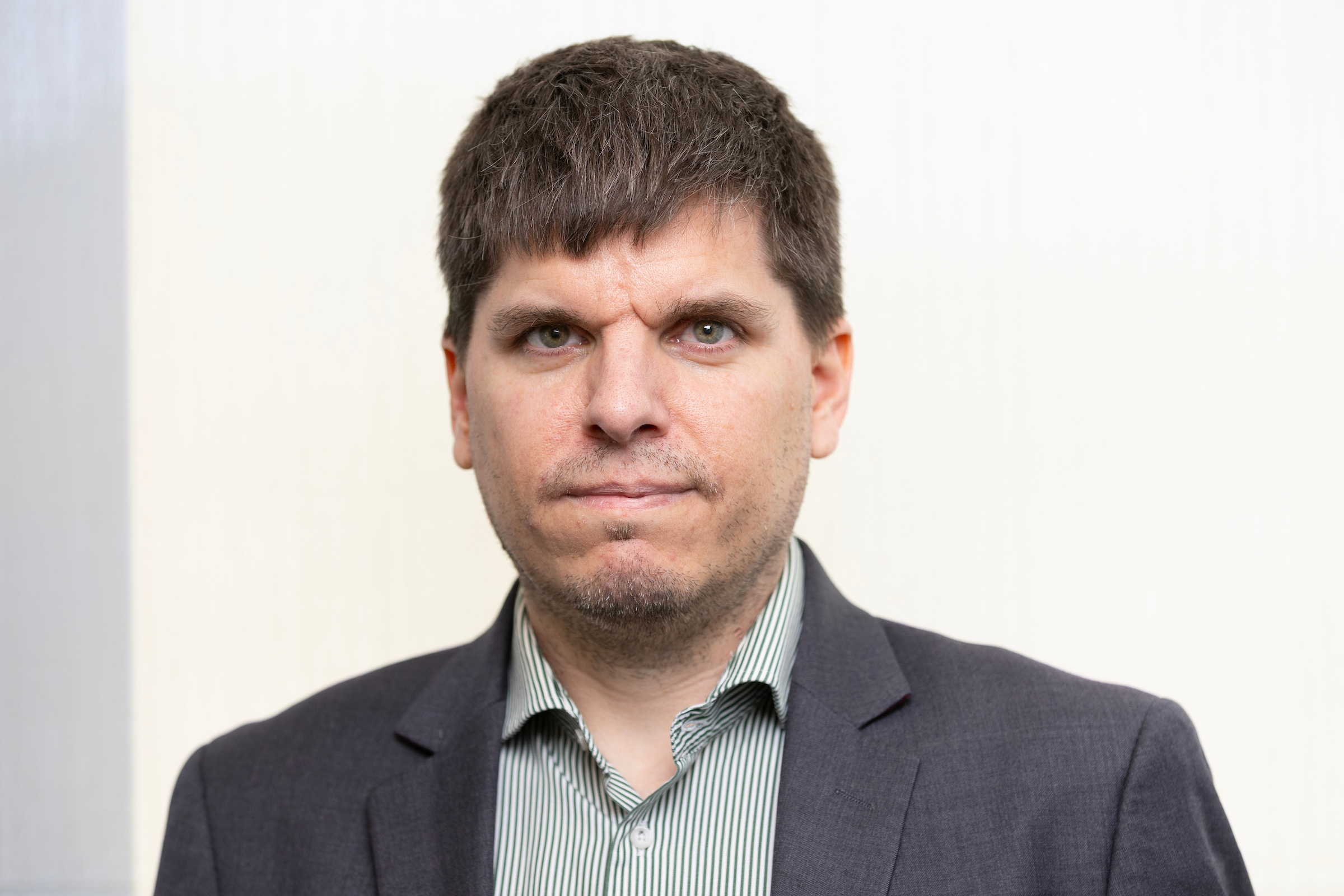 Color portrait of Iason Konstantzos, wearing a gray suit coat and striped shirt.