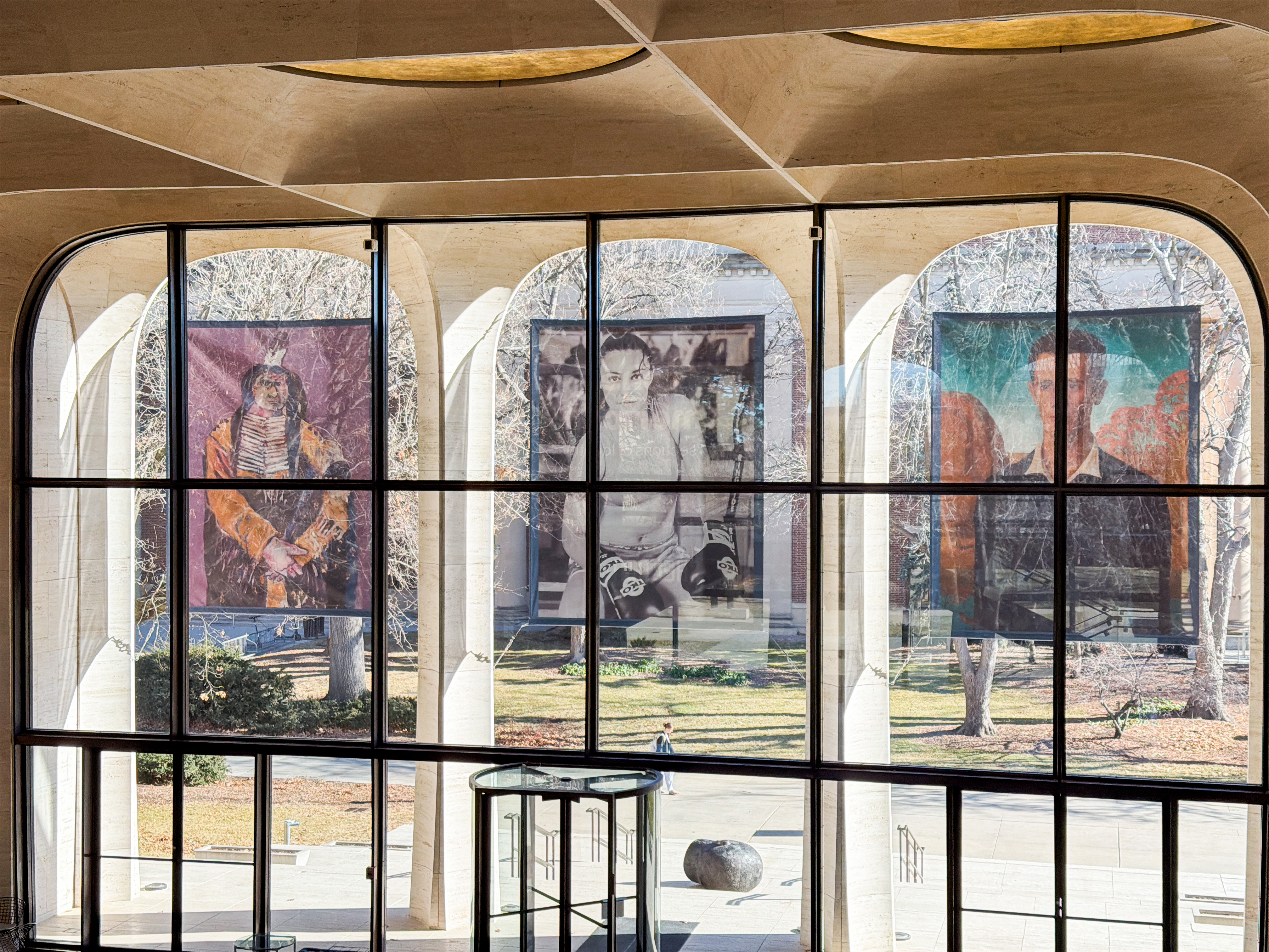 Three banners featuring people hang over the east windows of Sheldon Museum of Art.