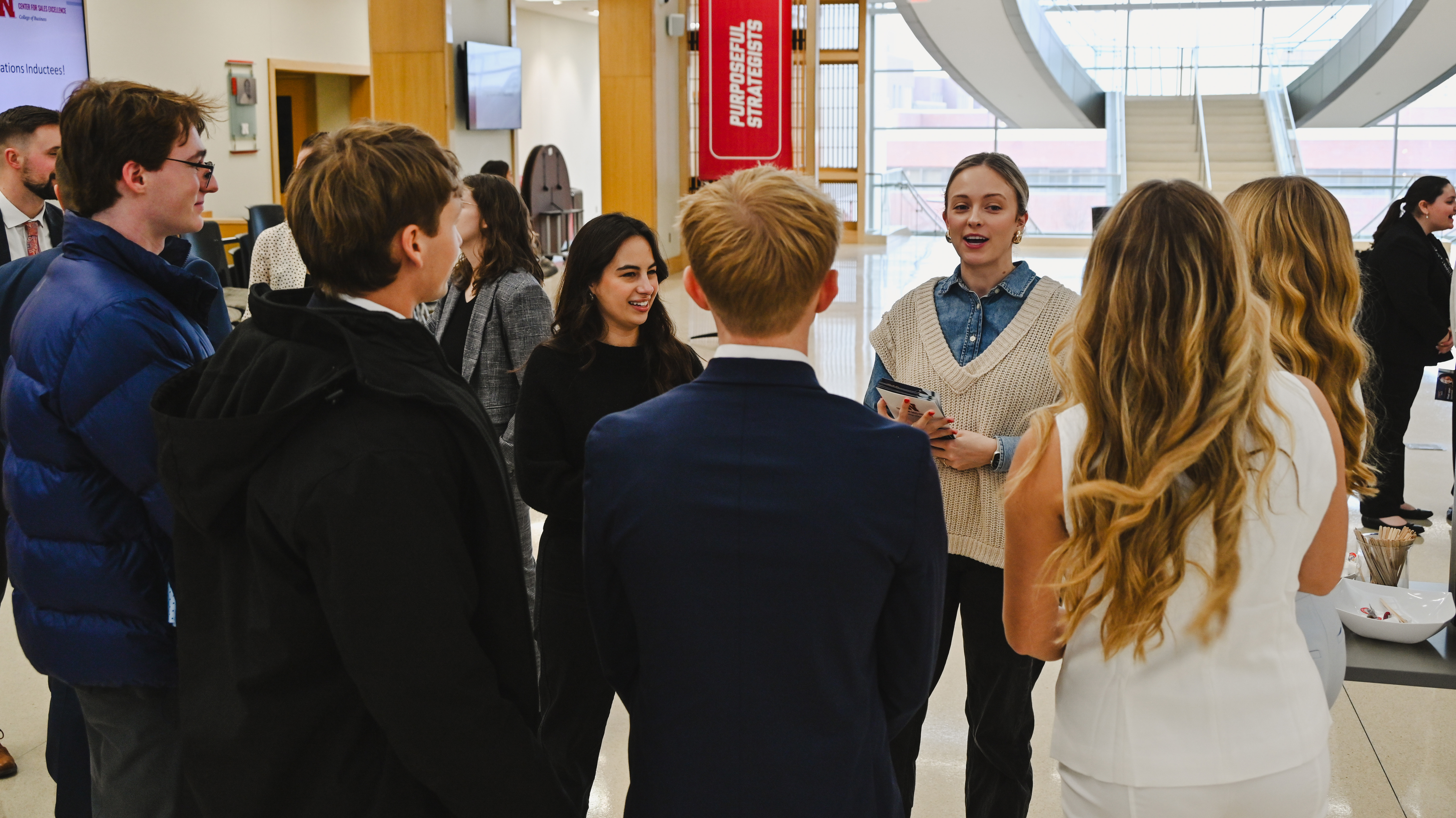 A young woman speaks to a group of University of Nebraska–Lincoln students in the atrium of Howard L. Hawks Hall.