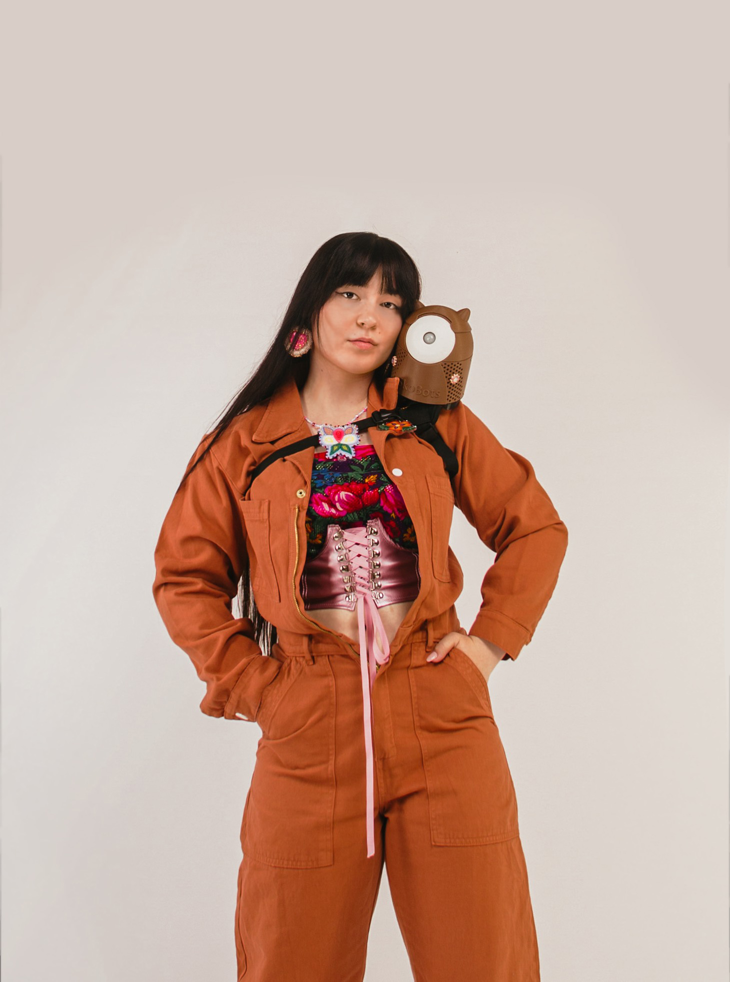 Color portrait of Danielle Boyer, wearing an orange jumpsuit, with a SkoBot robot on her left shoulder.