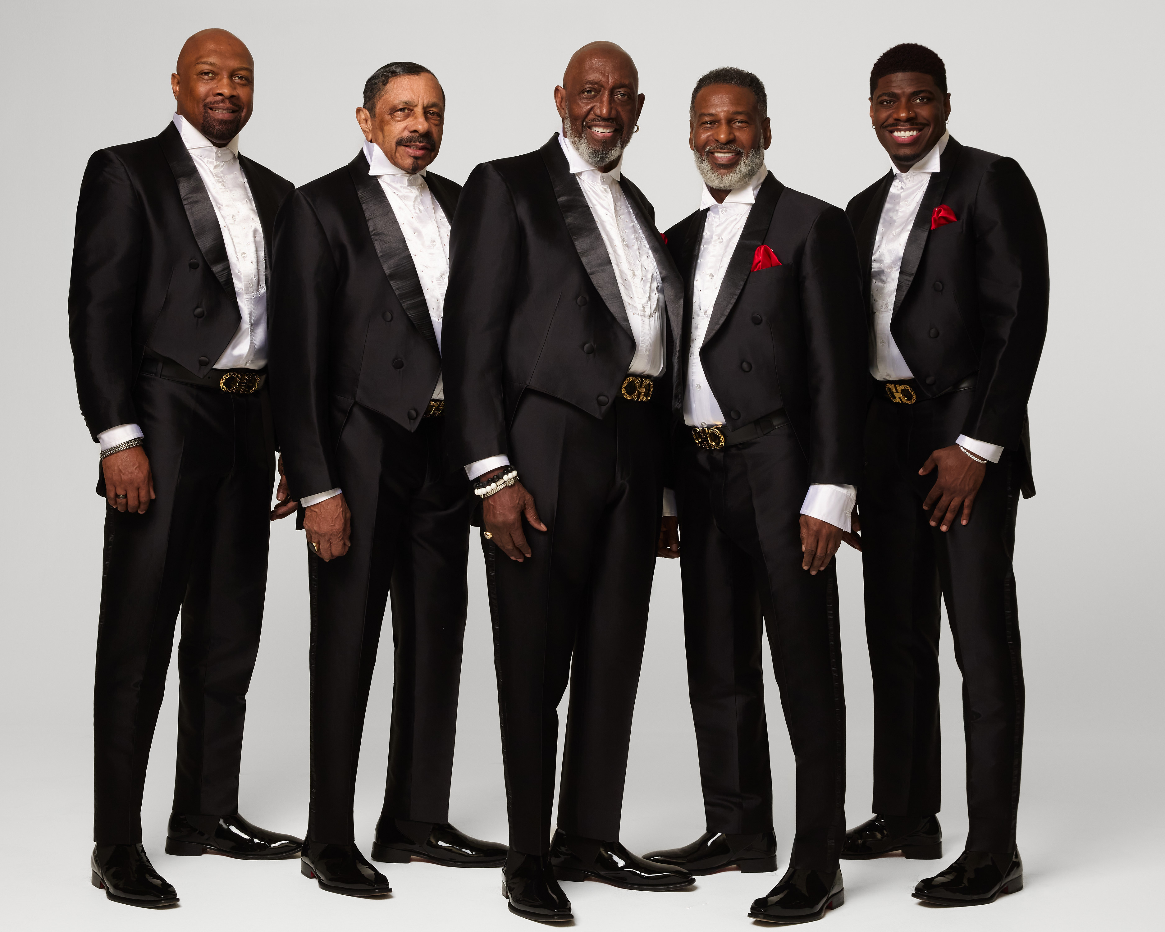 The Temptations — five men in matching black-and-white suits — pose for a group photo.