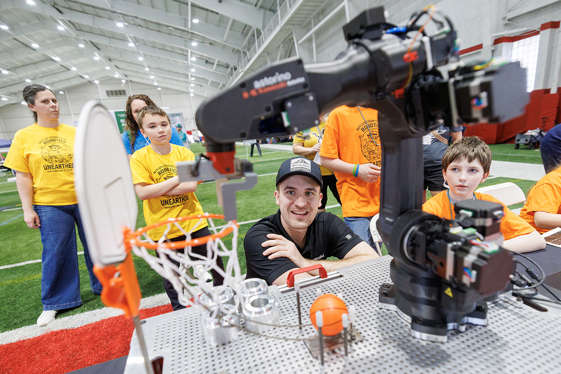 Students watch a robot move objects at an Industry Experience Table.