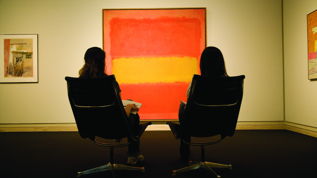 Two young women examine Mark Rothko's painting, "The Yellow Band," in the Sheldon Museum of Art.