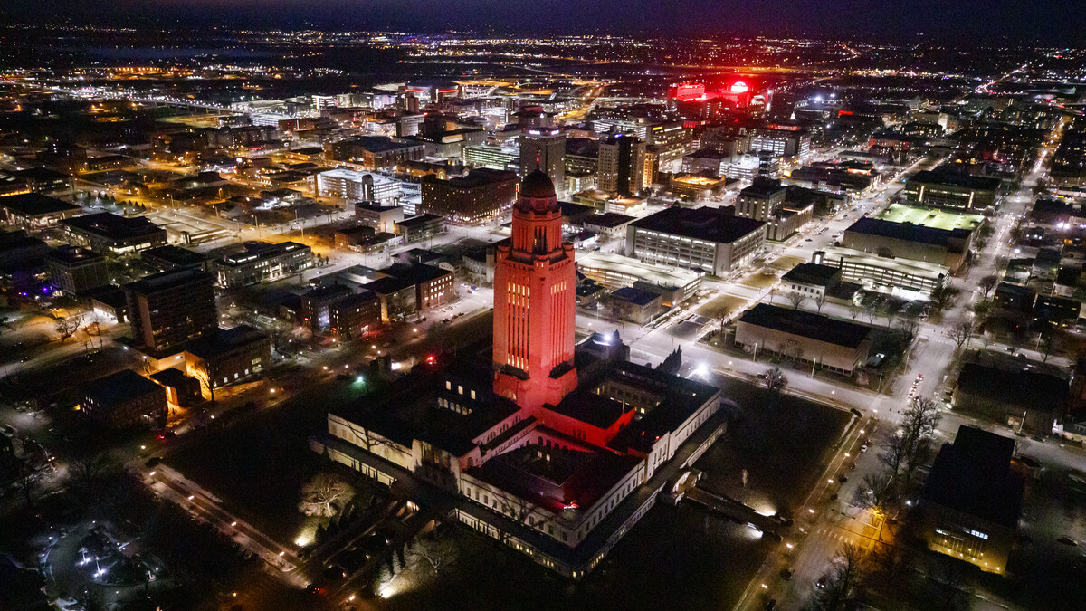 The Nebraska State Capitol shines red with Memorial Stadium and City Campus in the background.