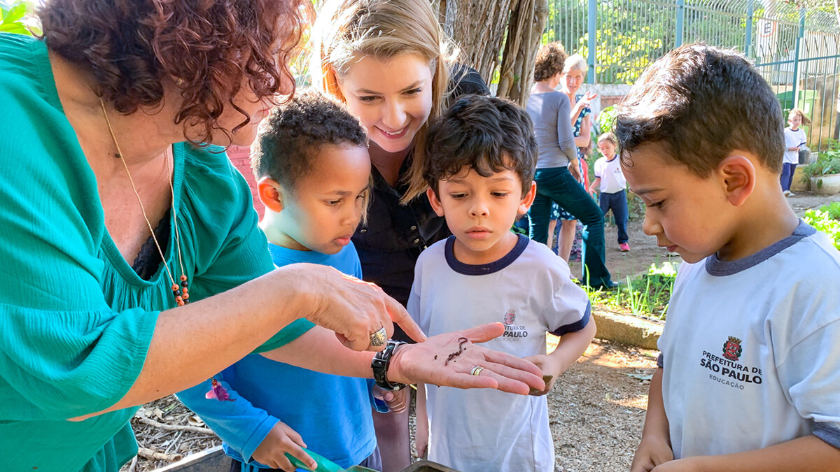 Teacher Elizinete Natália Queiroz de Araújo Souza (left) shows a worm to Nebraska graduate student Renata Gomes (center) and young students at EMEI Ignacio in São Paulo. 