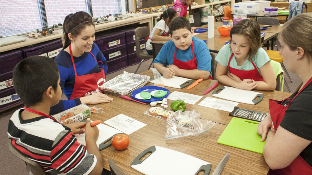 (From left) Giovanni Martinez, volunteer Denise McEnaney, Emmanuel Gallegos, Riah Zwicki and volunteer Julie Hegemann work on an exercise during the WeCook program Feb. 18 at West Lincoln Elementary.