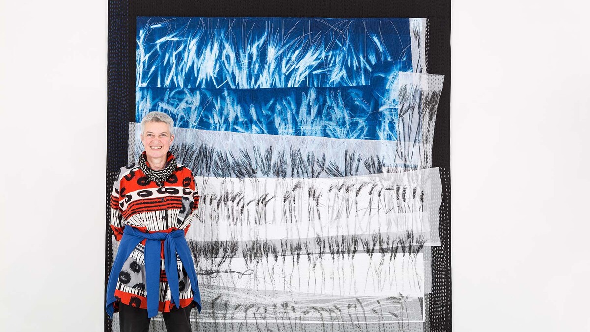 Quilt artist Pauline Burbidge poses with her 2016 work "Wheat and Barley Fields." The exhibition "Quiltscapes by Pauline Burbidge" will be on display from Oct. 14 through March 25 at the International Quilt Study Center and Museum.