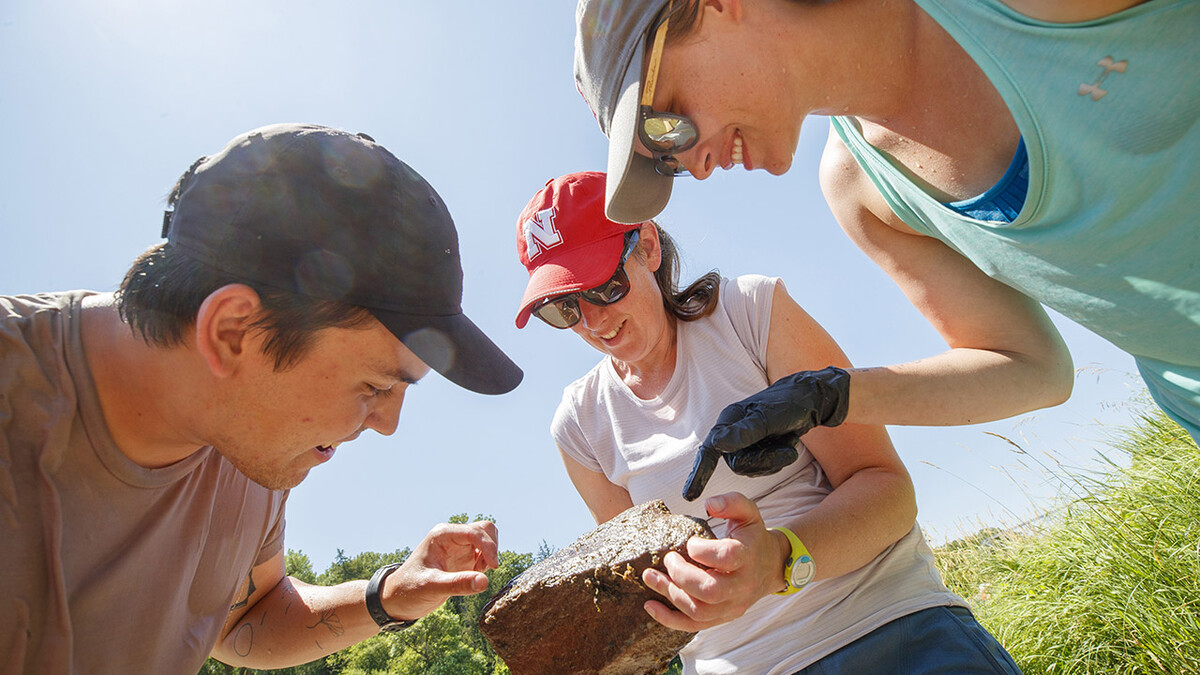 Jessica Corman (center), assistant professor in the School of Natural Resources, discusses a rock teaming with aquatic life with students Matthew Chen and Kayla Vondracek during a UCARE project on the Niobrara River in July 2019.