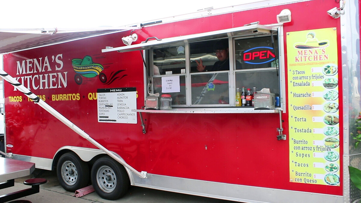 Employee makes peace sign from inside Mena's Kitchen food truck