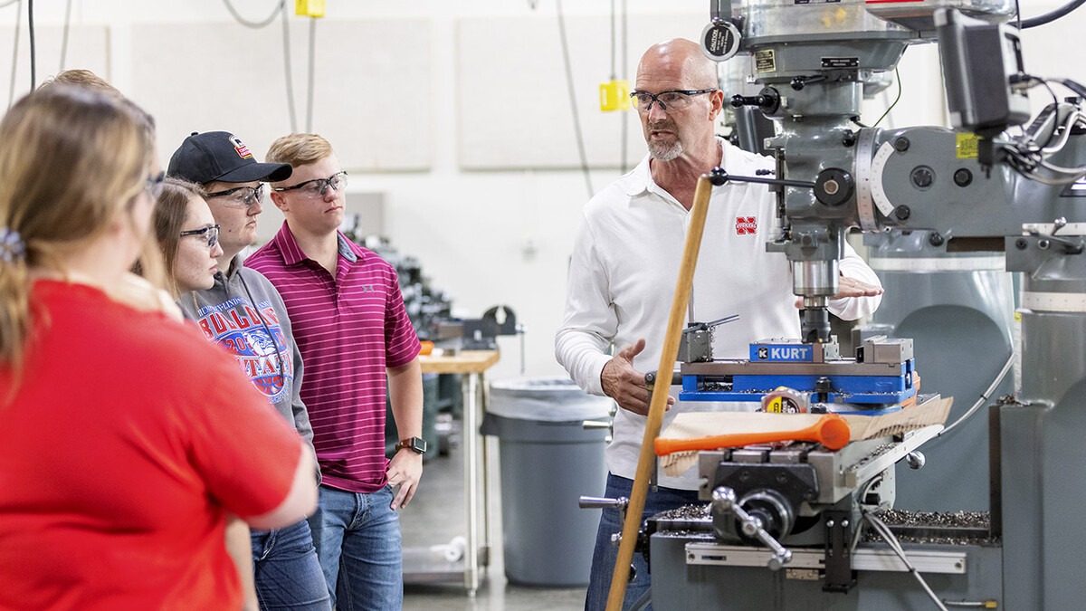 Eric Knoll stands next to several students, with everyone wearing safety glasses