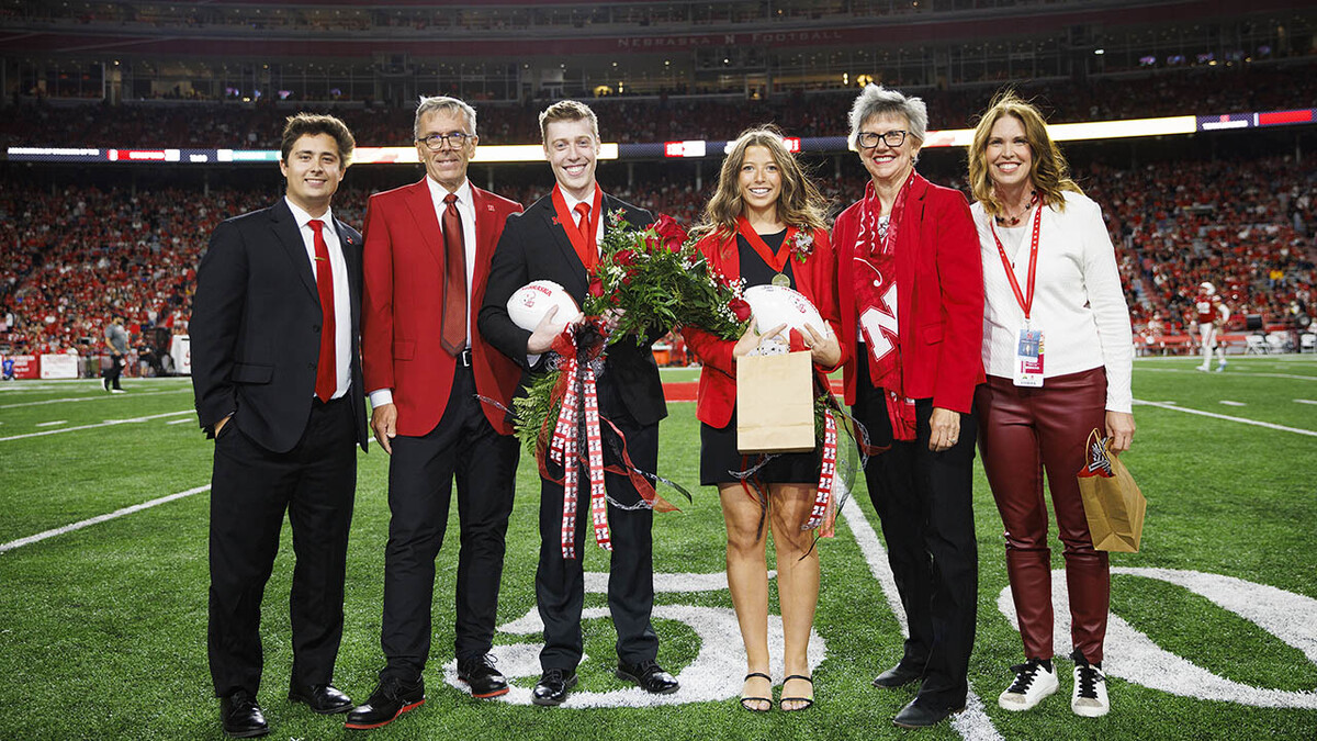 Newly crowned homecoming royalty Jacob Drake (third from left) and Emily Hatterman (fourth from left) are joined by 2021 royalty Bobby Martin (left), Chancellor Ronnie Green (second from left), Jane Green (fifth from left) and Nebraska Alumni Association Executive Director Shelley Zaborowski (right).