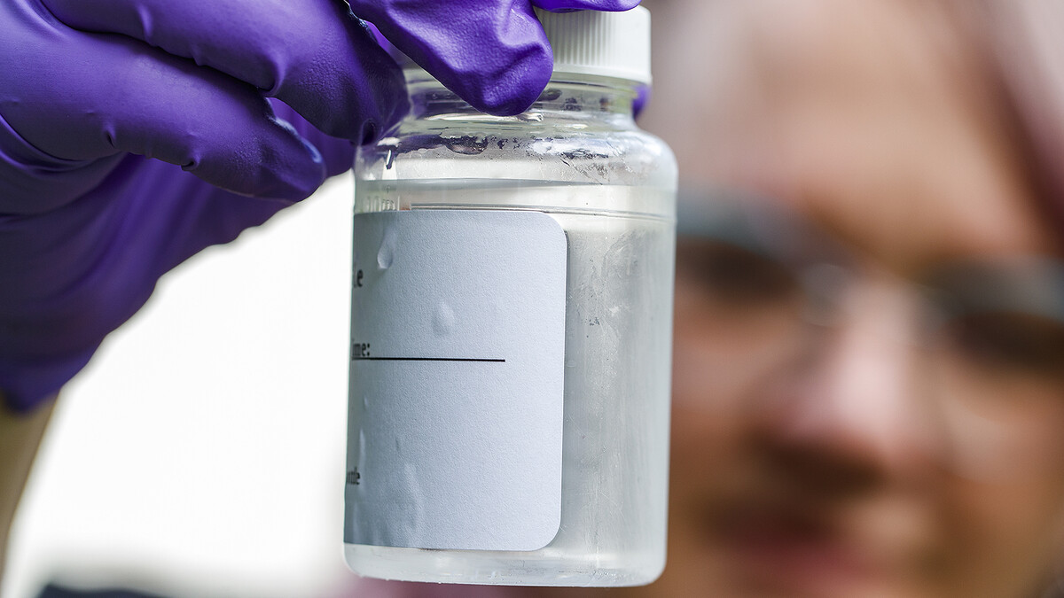 Woman holds a small bottle with water sample