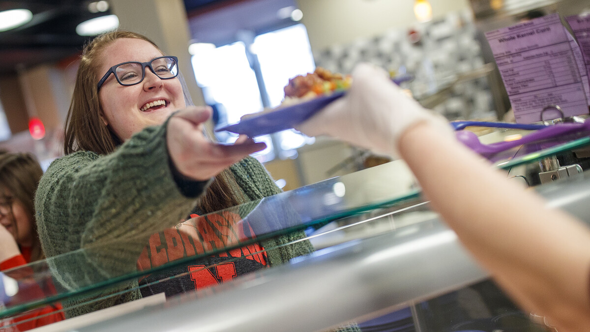 A female student receives a plate of food from a Harper Dining Center employee.