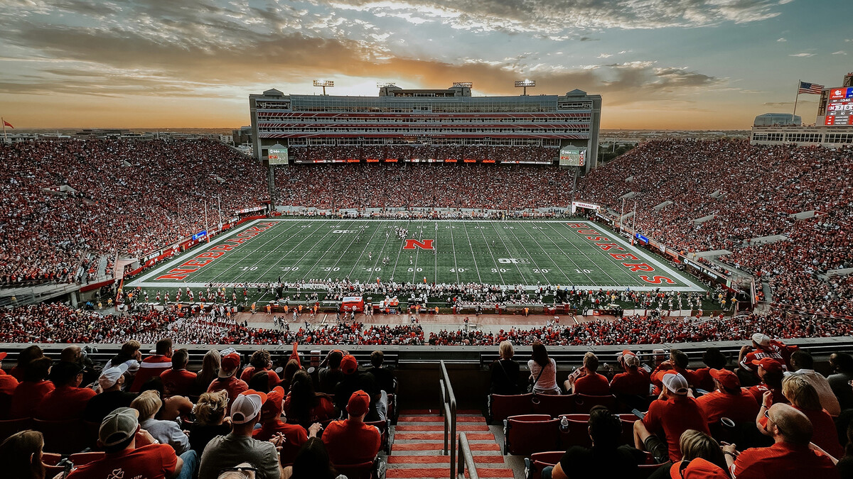 Memorial Stadium, full of fans, with colorful clouds in the background