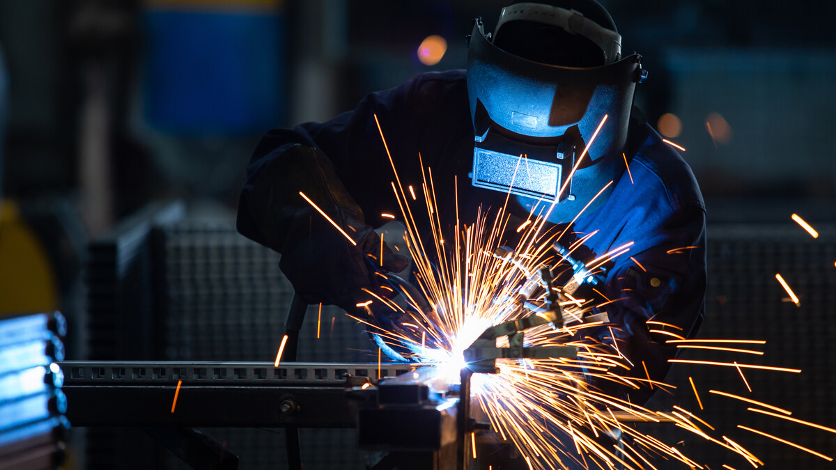 A welder in a mask throws sparks.