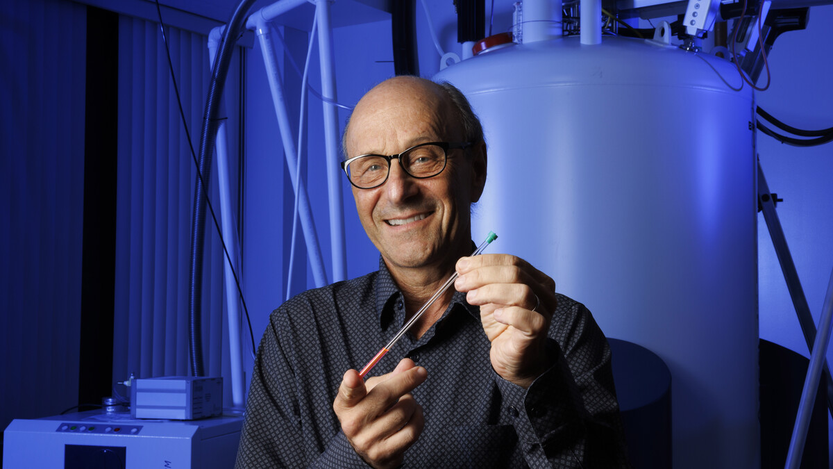 David Berkowitz holds a nuclear magnetic resonance tube in a lab.