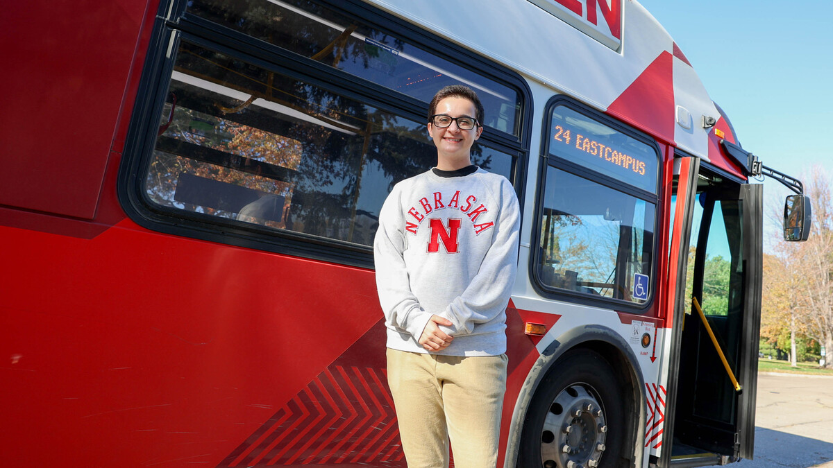 Andrew Dominguez Farias stands next to a red-and-white StarTran bus.