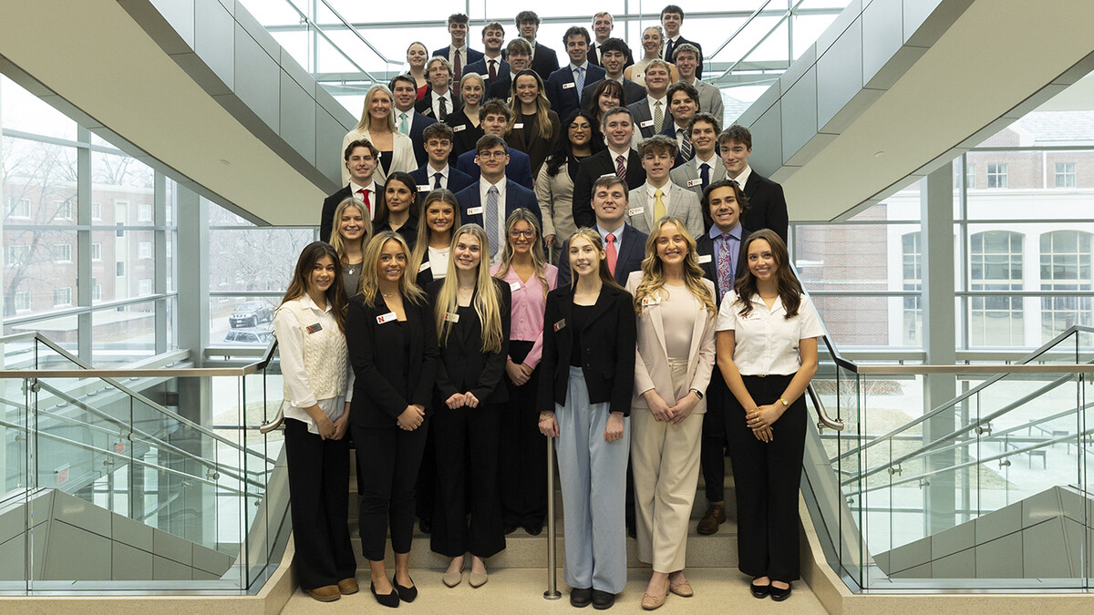 Thirty-plus Husker students pose on a staircase in Howard L. Hawks Hall.