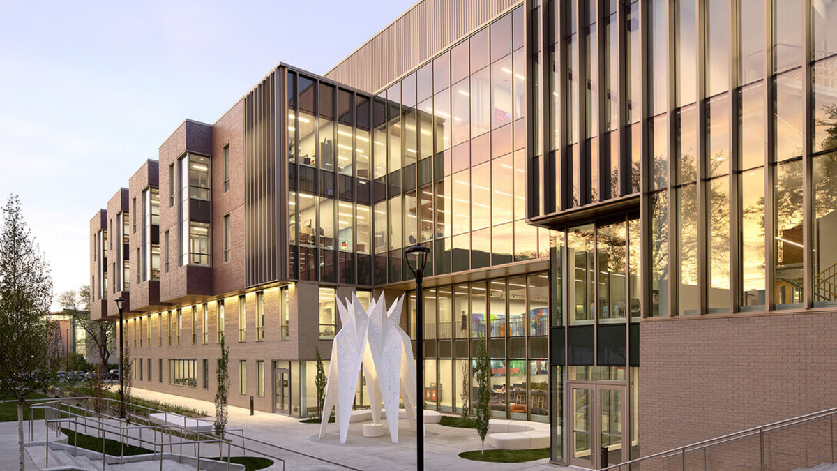 Exterior photo of the west side of Carolyn Pope Edwards Hall, a brick building with numerous windows and a white paper-plane sculpture in front.