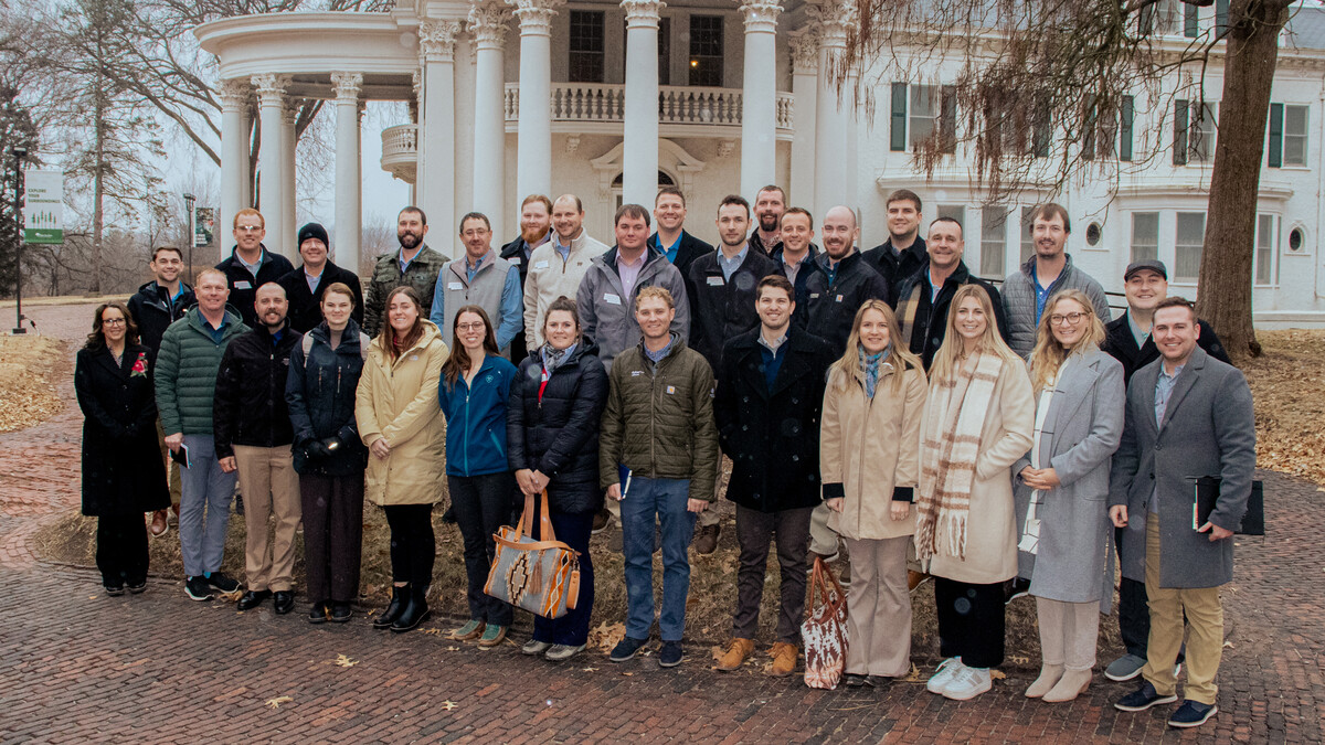Thirty people in cold-weather clothing stand outside the Arbor Lodge mansion.