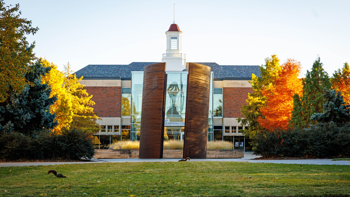 The "Greenpoint" sculpture is seen north of the Love Library cupola on a fall afternoon, as two squirrels scurry about in the grass.