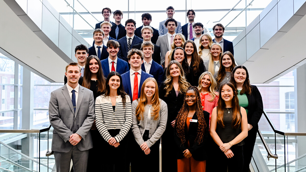 A group of about 30 University of Nebraska-Lincoln students in formal attire pose on a staircase in Howard L. Hawks Hall.