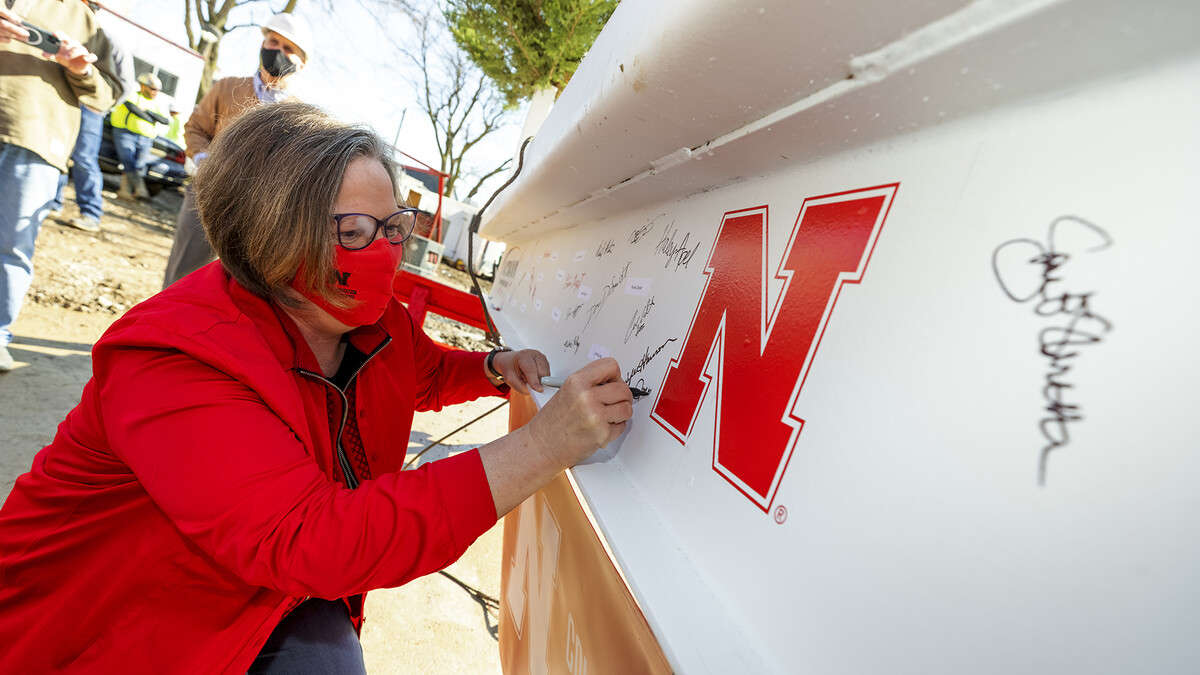 Sheri Jones, dean of the College of Education and Human Sciences, signs the final beam that was lifted into place during the April 9 topping out ceremony. An evergreen tree was also placed atop the beam, signifying the safe completion of the internal structure of the building.