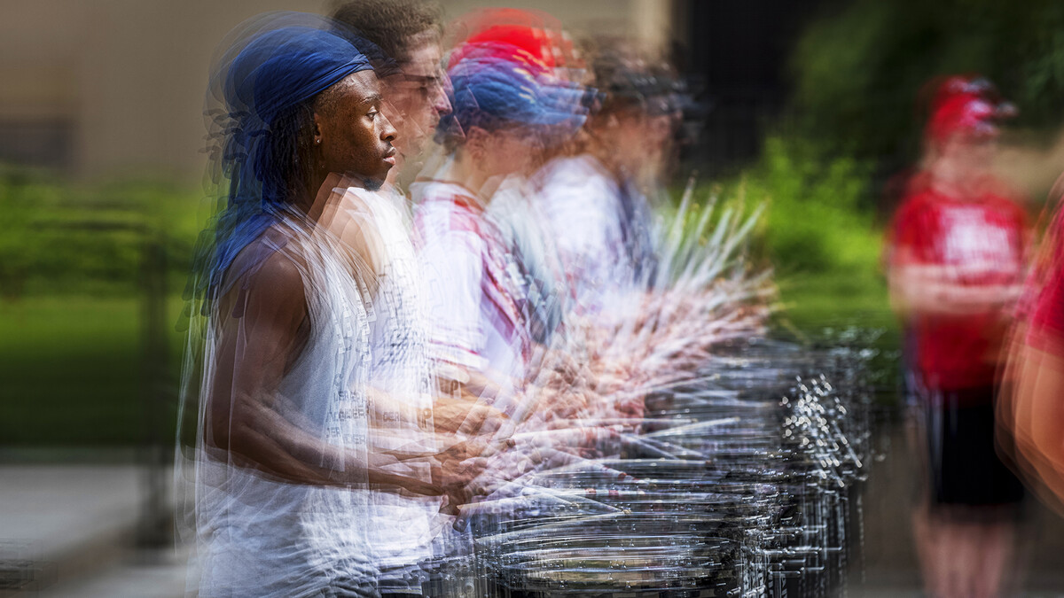 Multiple exposure image of Cornhusker Marching Band snare drum players practicing on campus.