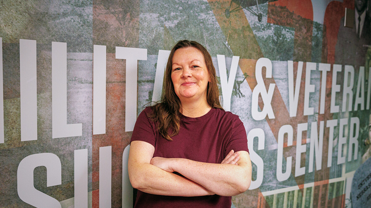 A woman stands in front of a mural.