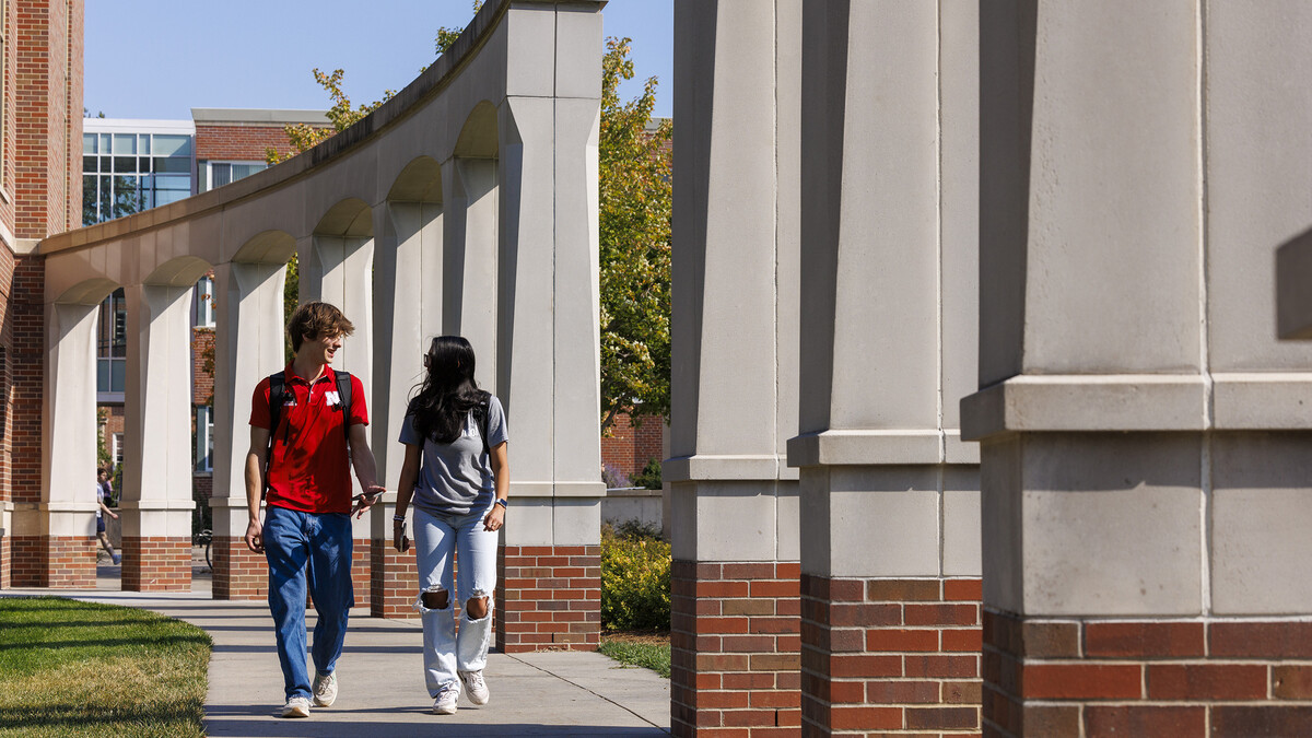 Raikes School students Gannett Bishop and Nina Glick walk along the columns outside of the Kauffman Academic Residential Center.