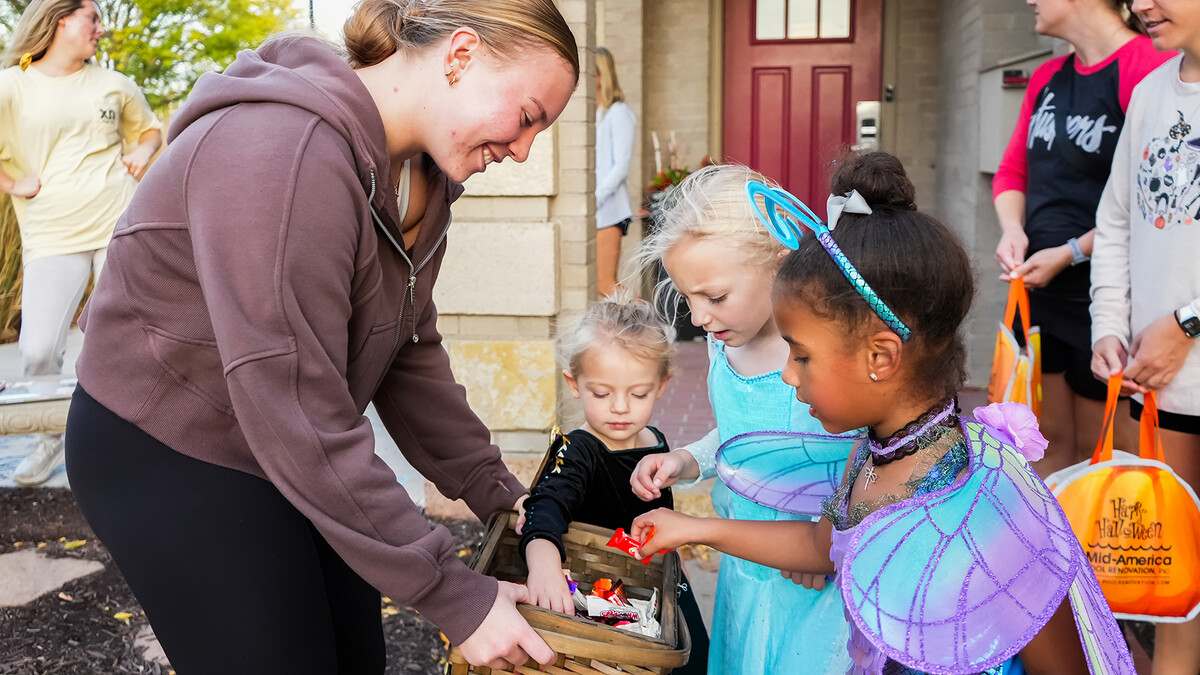 Lyndee Friedrich, a sophomore in the pre-health program, dishes candy treats to children at the Chi Omega sorority as part of Greek Street Trick-or-Treat on Oct. 29.