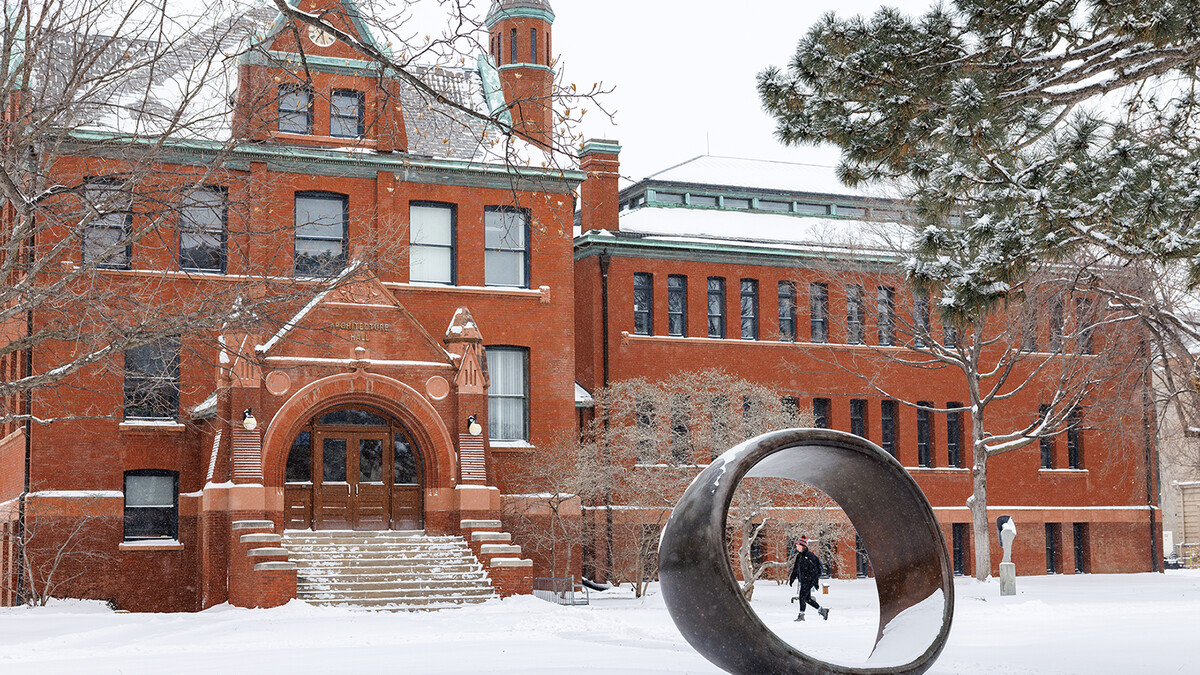 A student walks past Architecture Hall as snow falls on the morning of Feb. 12. The winter storm closed campus for the day, and classes and work shifted to remote formats.