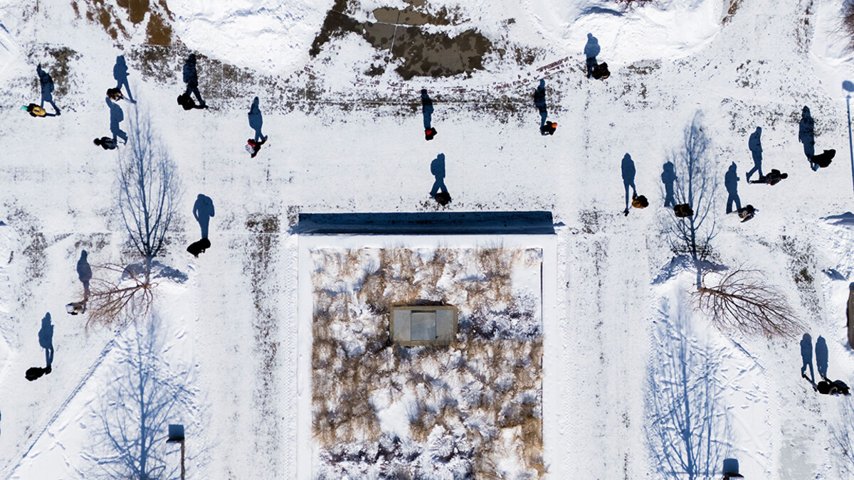 Student’s shadows are cast onto the snow as they walk past the Adele Learning Commons. February 19, 2025. 