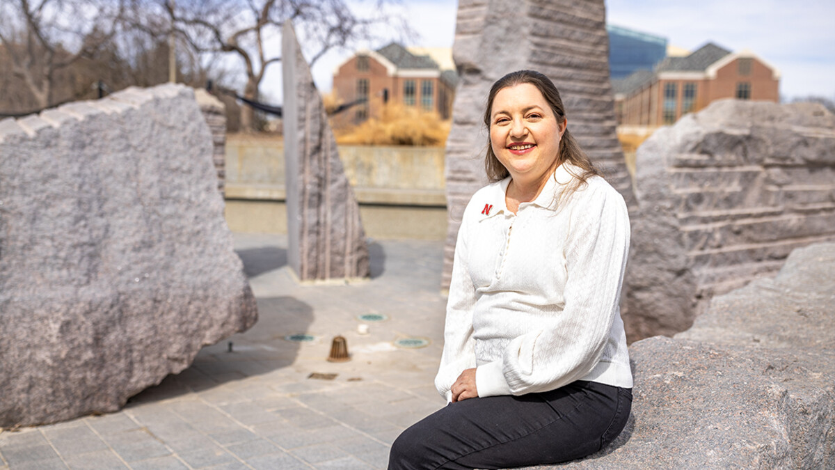 Courtney Santos, the director of Undergrad Research and Fellowships and an educational psychology graduate student, sits by Broyhill Fountain outside the Nebraska Union.