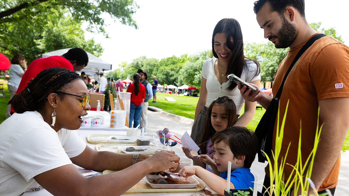 Bellodgia Roberson, a graduate student studying agriculture and horticulture, helps three-year-old Jasper Molina make a soil profile during Discovery Days and Farmers Market on June 14. 