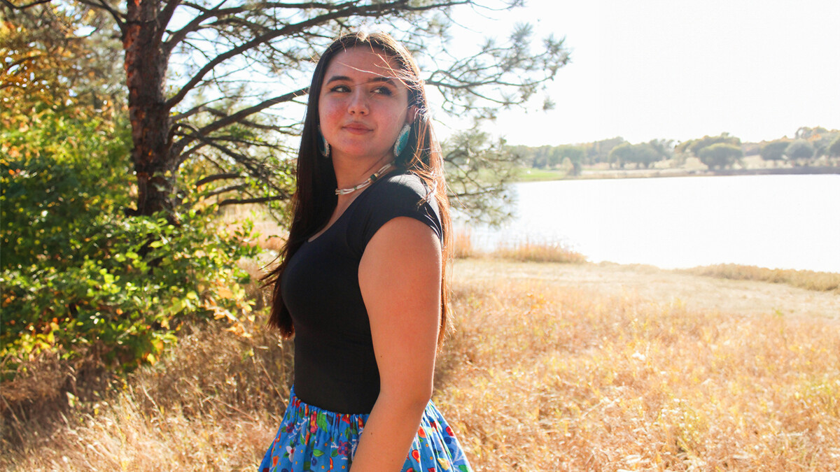 Carlee Rigatuso standing outside by a lake.