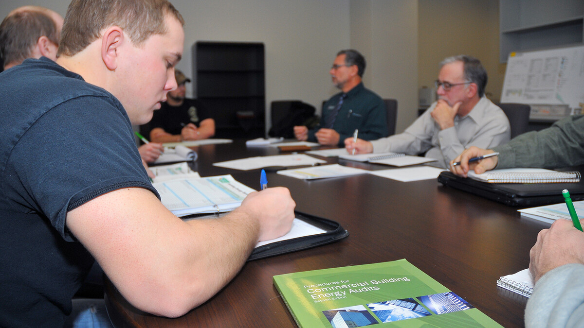 UNL engineering students write down answers during an interview with Kirk Conger. The students are conducting energy audits of UNL buildings as part of a pilot course in engineering.