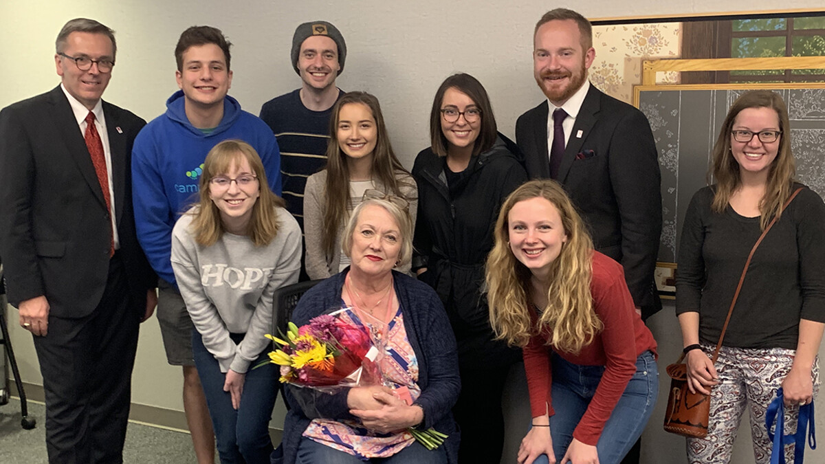 Chancellor Ronnie Green (left) and Huskers who have earned major fellowships gathered to celebrate the work of Laura Damuth (seated, with flowers) on April 18. Emily Johnson (hands on knees, at right) helped with the surprise by scheduling a meeting with Damuth.