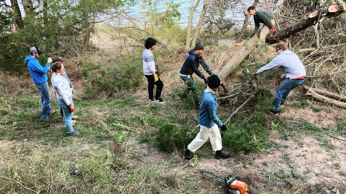 Chaining and dragging out trees, students prep the site at the Cedar Point Biological Station for a from scratch build.