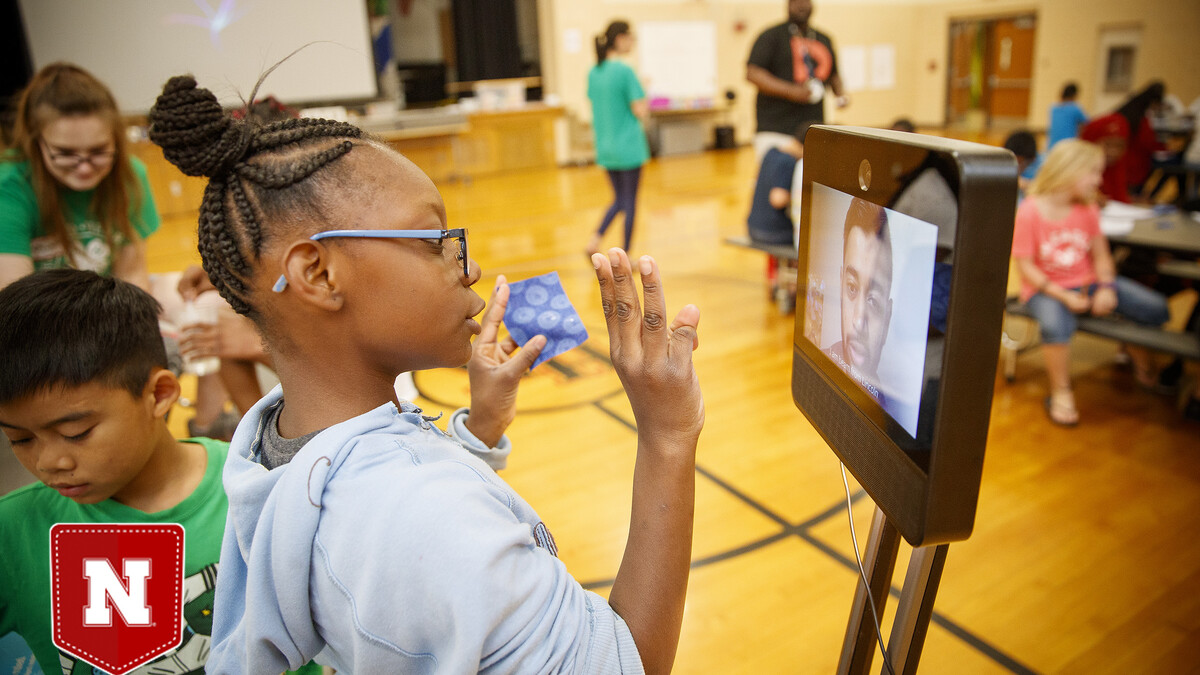 Ani'a Morris-Gordon interacts with Soham Patel, a UNL computer science major, who is using Beam technology to remote teach the class about nano technology and nano treated fabrics.