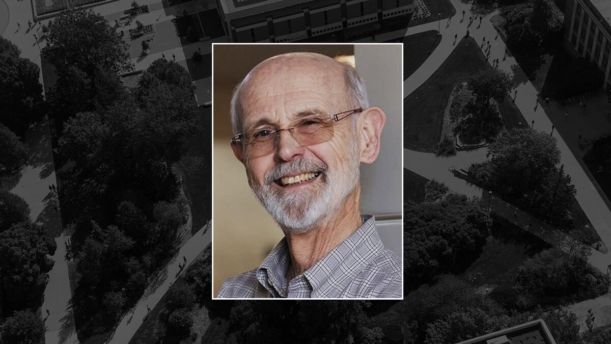 James Potter, a white man with grey hair on the sides of his head and a grey beard, smiles in rectangular glasses.