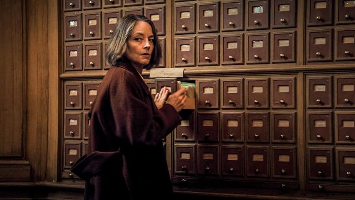 A psychiatrist, played by Jodie Foster, who has a gray bob, wears a brown coat as she opens a small file drawer.
