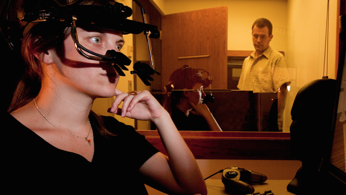 In this file photo, UNL psychology professor Michael Dodd (background) observes a study participant equipped with eyetrack technology.