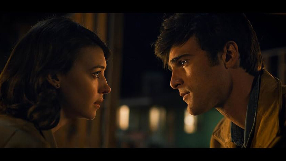 A brunette woman and a brunette man gaze intensely at each other in a film still.